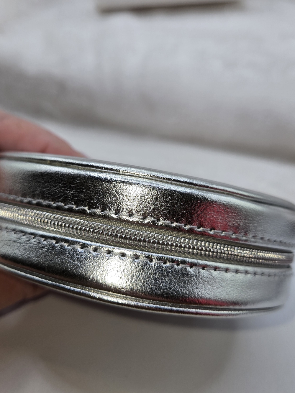 Round cosmetic pouch in metallic silver finish featuring raised logo - Picture 4 of 6